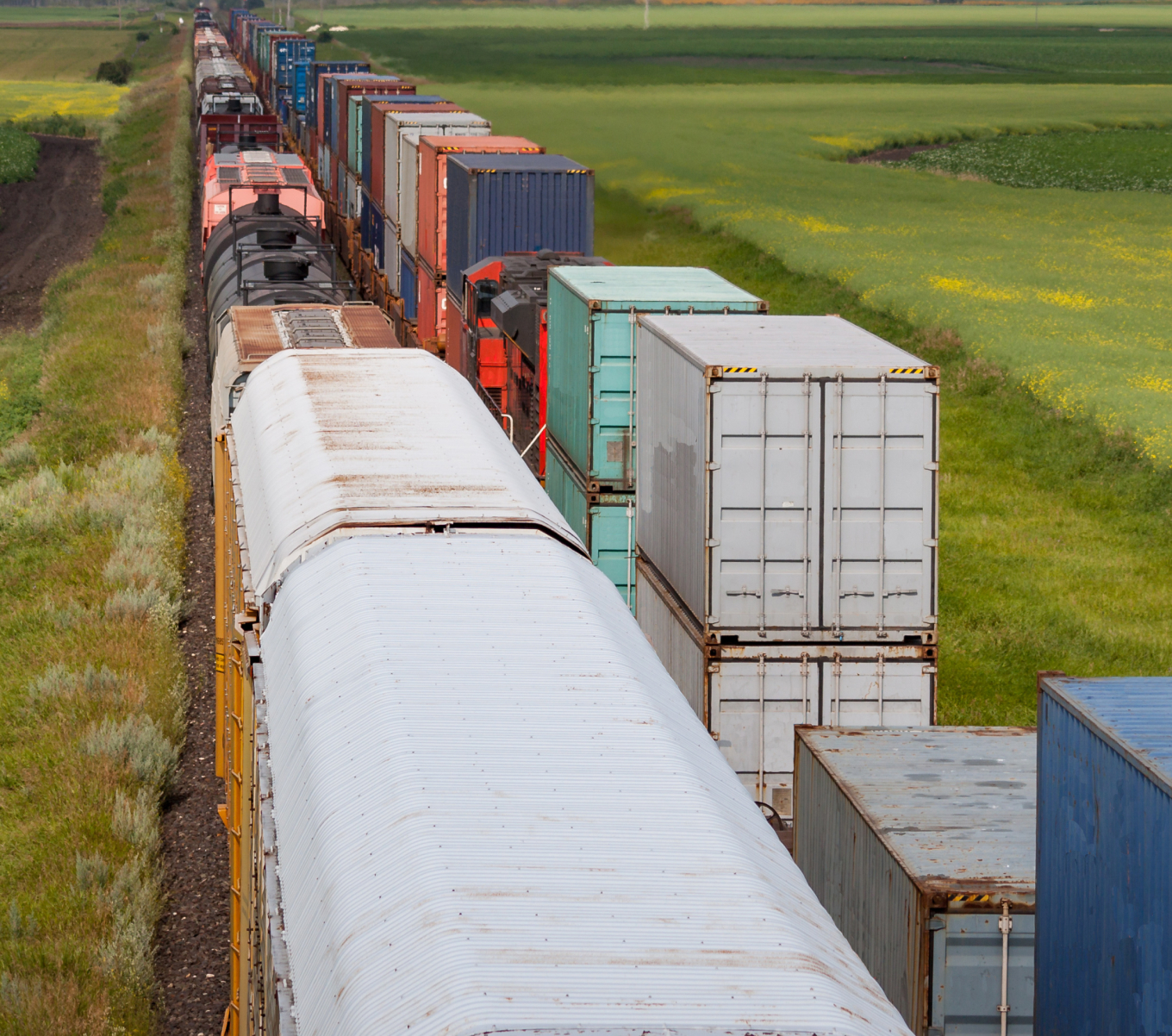 Various types of railcars, including tank cars and box cars, line a railyard