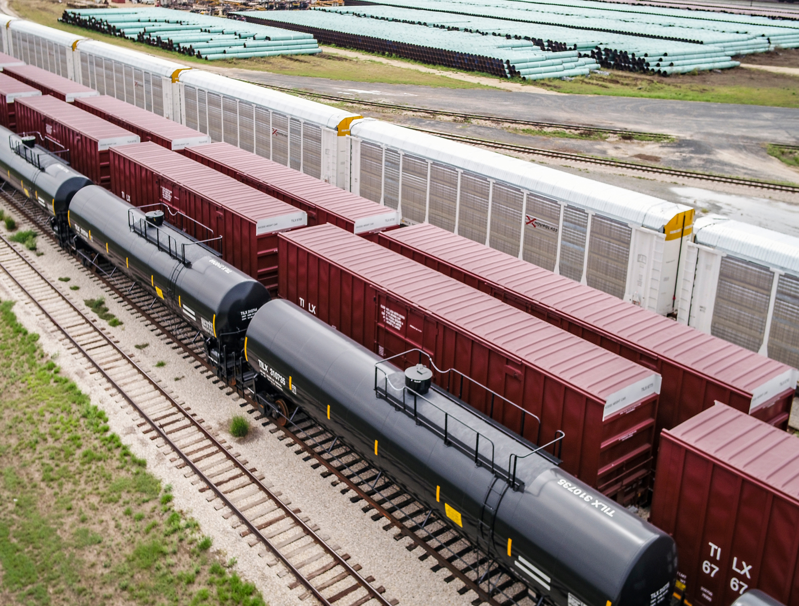 Various types of railcars, including tank cars and box cars, line a railyard