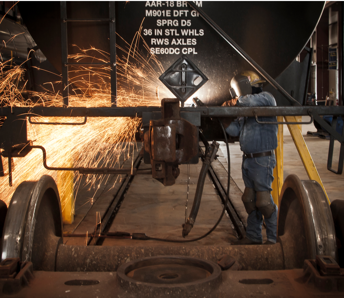 A welder works on a railcar axle